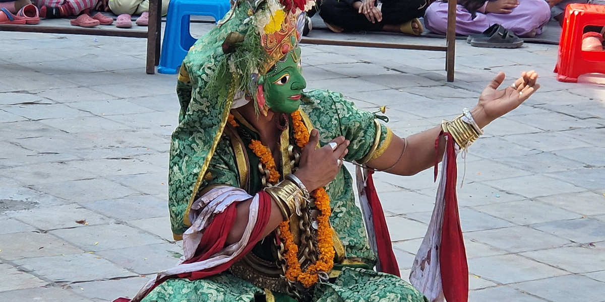 A Nepalese dancer wearing a green mask and colourful costume