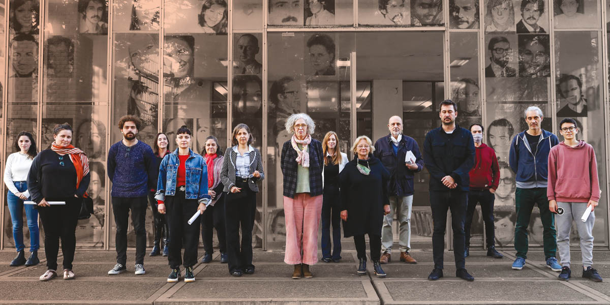 A large group of people stand outside a glass fronted bulilding, the ESMA Memory Museum in Buenos Aires, Argentina
