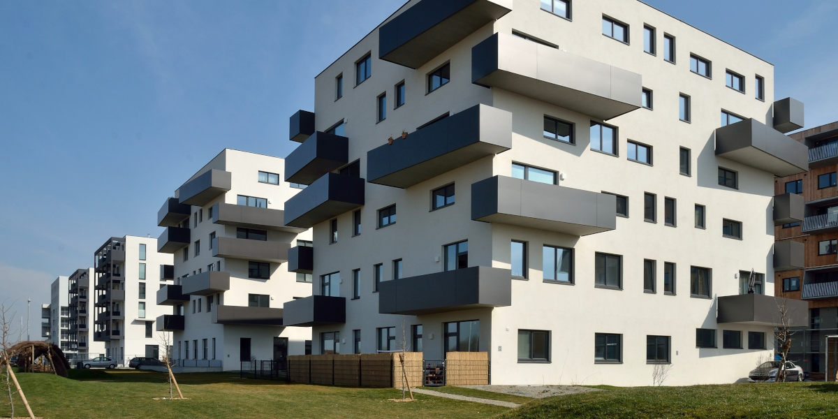 A modern, white apartment building set against a blue sky in the Aspern Seestadt neighborhood of Vienna, Austria