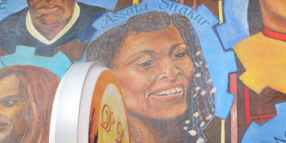 A mural depicting Assata Shakur above a storefront