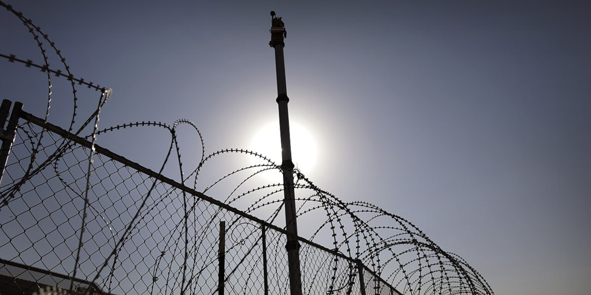 An autonomous surveillance tower on the US-Mexican border, with barbed wire fencing in the foreground