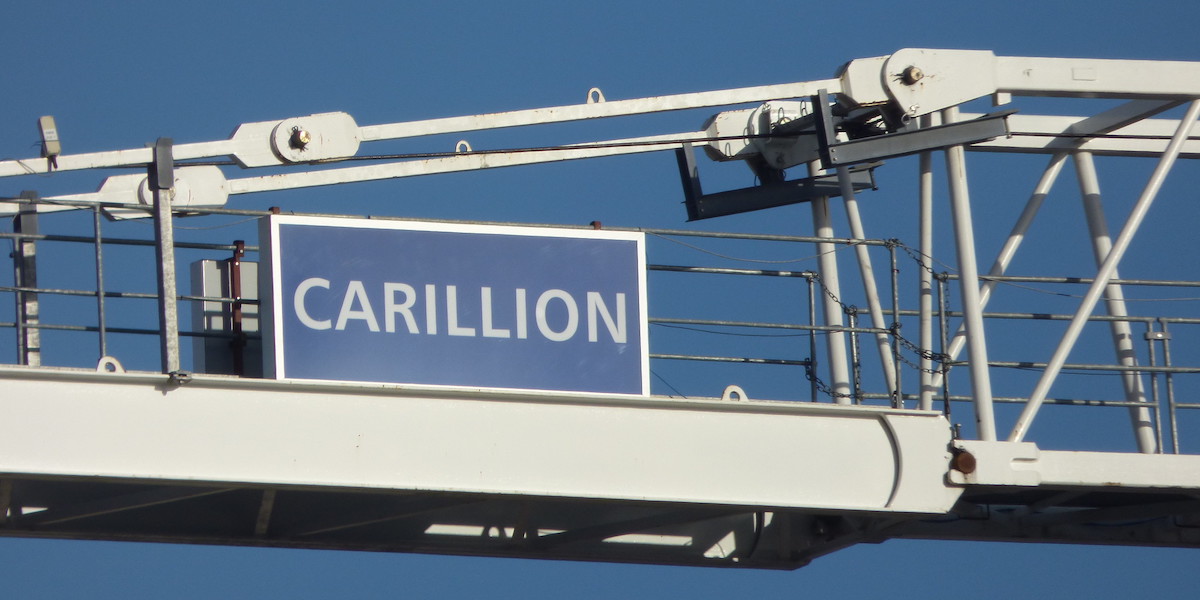 A close up of a brand sign reading 'CARILLION' on the side of a white crane, against the blue sky