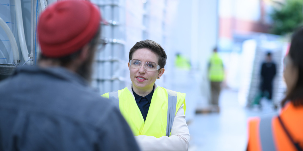 Green Party co-leader Carla Dreyer wearing googles and a high vis vest talking to independent businesses in Bristol