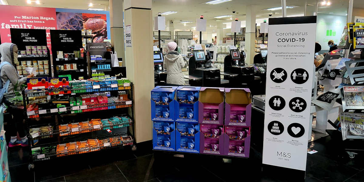 A Marks and Spencer supermarket checkout with a COVID-19 social distancing sign in the foreground