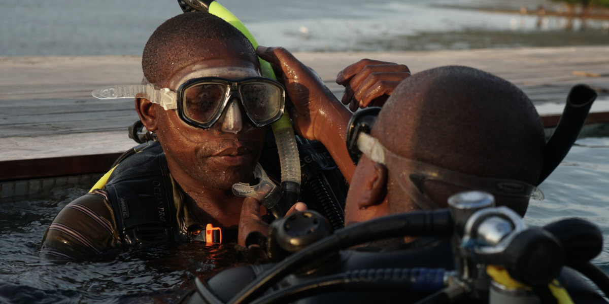 Two divers emerging from the water facing each other