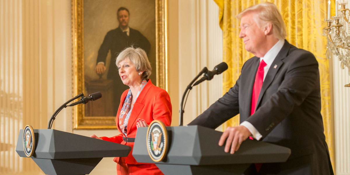 Former UK Prime Minister Theresa May at a press conference with US President Donald Trump, both stood at lecterns with microphones
