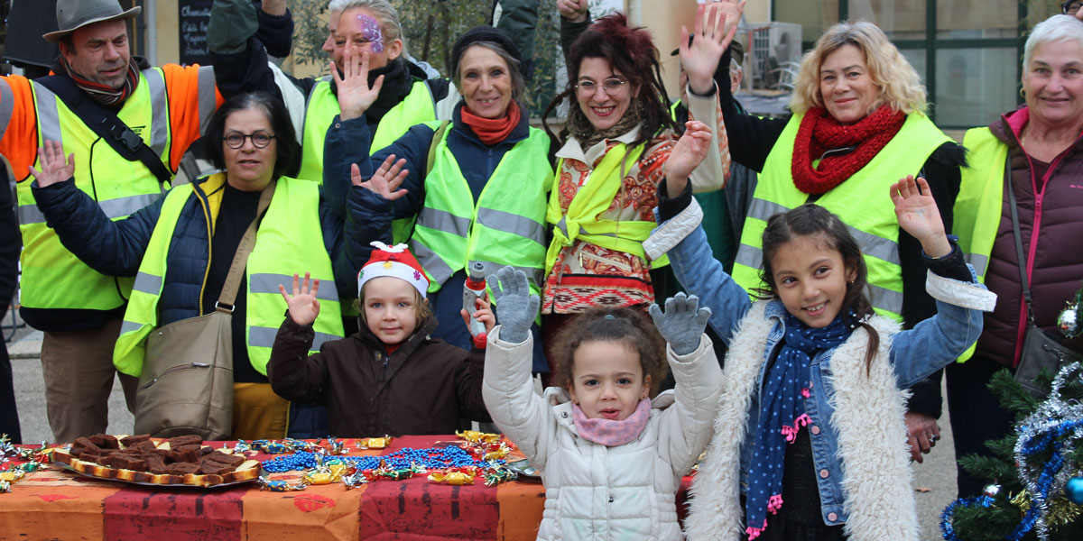 A group photo of people waving, with children in the foreground and adults in the background wearing fluorescent yellow vests