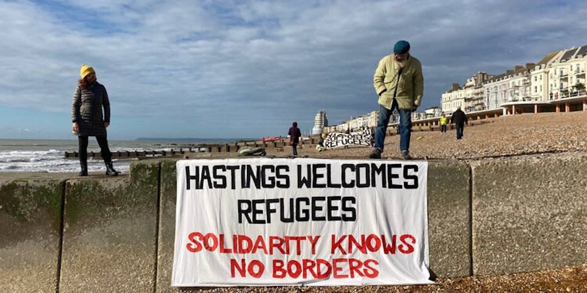 Campaigners from the Refugee Buddy Project in Hastings show solidarity with migrants arriving in small boats by displaying a banner on the beach during Solidarity Knows No Borders week 2020