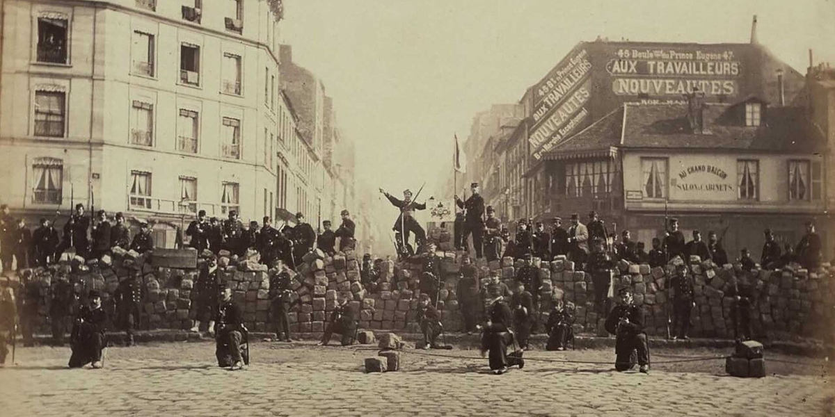 A contemporary black-and-white photograph of communards posing for a photograph in front of and along a barricade during the 1871 Paris Commune