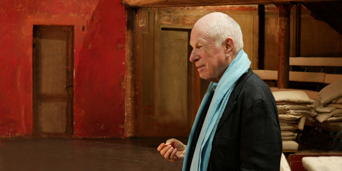 The director Peter Brook is shown in profile in a theatre