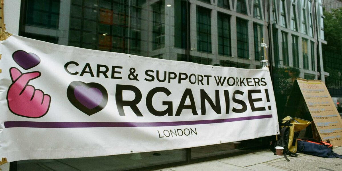 Banner outside office building reading 'Care & Support Workers Organise'