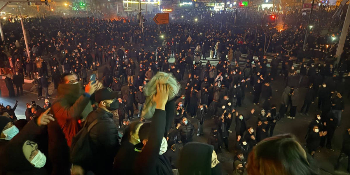 A crowd protesting against the government in Iran, most with their faces covered