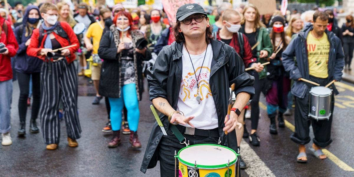 The author drumming with a band at a protest in London, August 2021