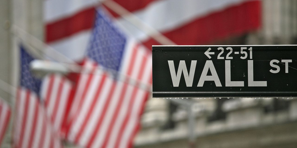 A photograph of the New York Stock Exchange, with the Wall Street street sign in the foreground and the stock exchange in the background