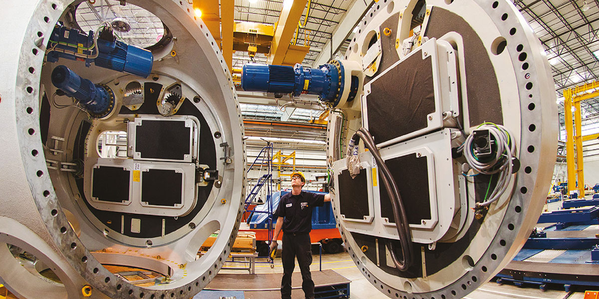A worker stands in between huge engines in a factory