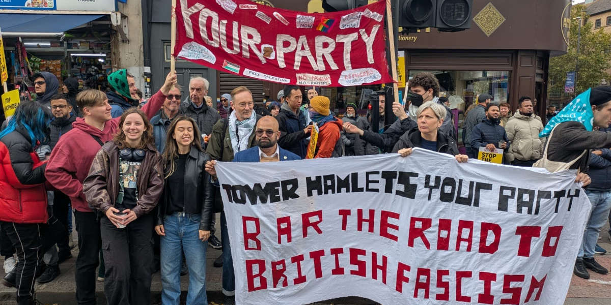 A group photo of members of Your Party's Tower Halmets group with anti-fascist banners